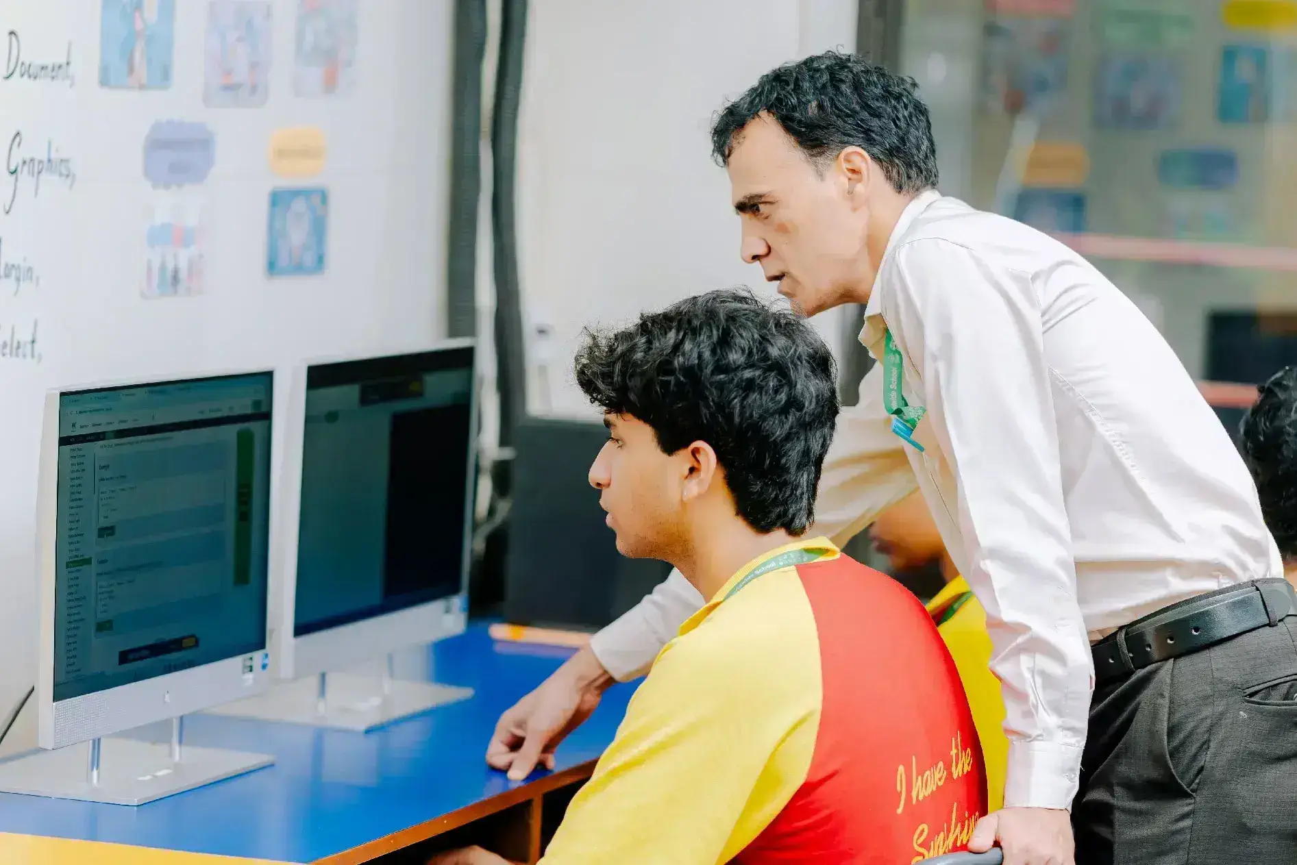 Teacher guiding student at computer screen